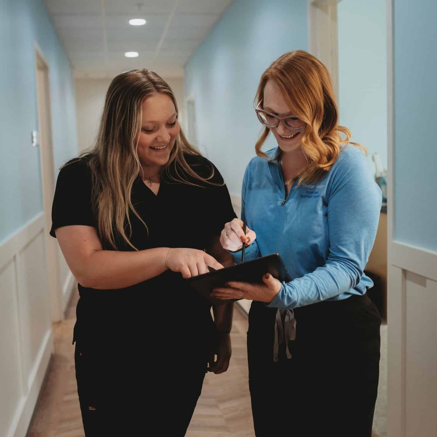 Two women discussing hearing solutions at Tinnitus Relief + Advanced Audiology Center.