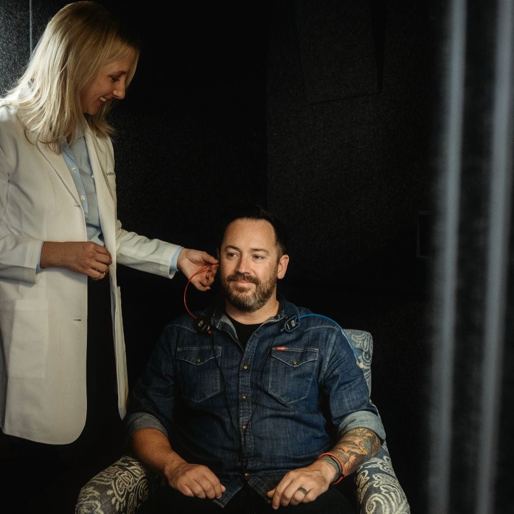 Audiologist fitting hearing device for patient at Tinnitus Relief Center.