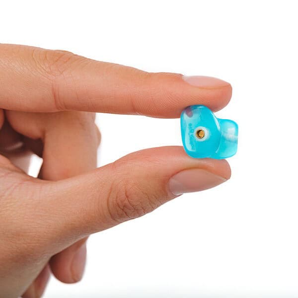 Blue hearing aid device held between fingers for tinnitus relief.