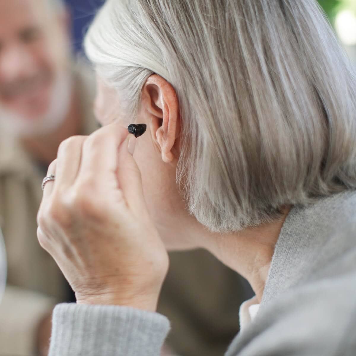Elderly woman undergoing a hearing test with an audiologist.